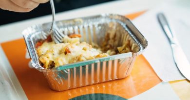 Gros plan sur un petit plat en aluminium avec de la nourriture gratinée.