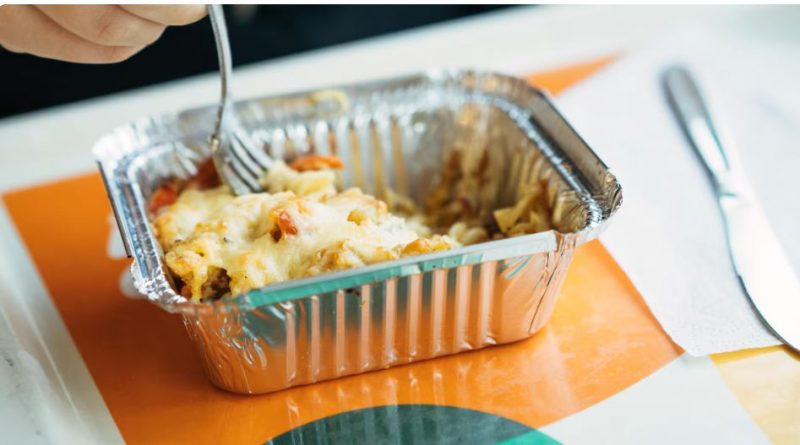 Gros plan sur un petit plat en aluminium avec de la nourriture gratinée.
